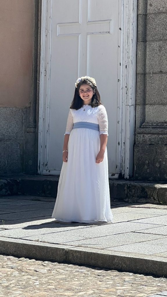 Niña con el vestido de comunión posando frente a iglesia