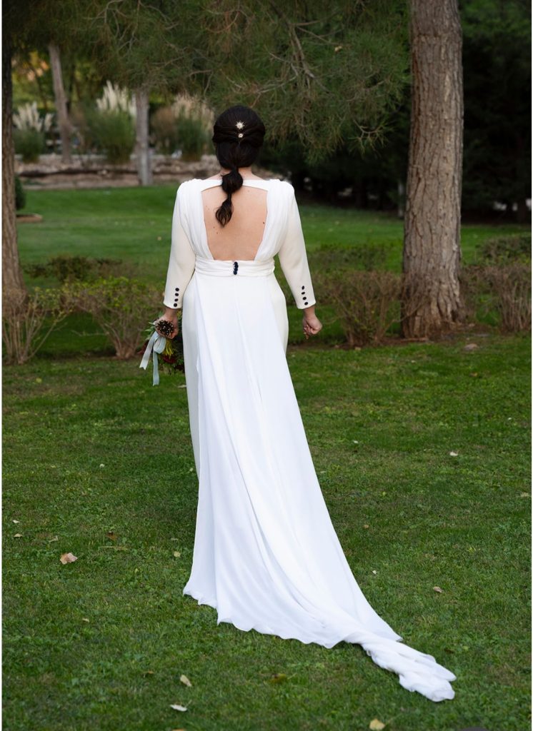Novia en el campo posando con el vestido de espaldas