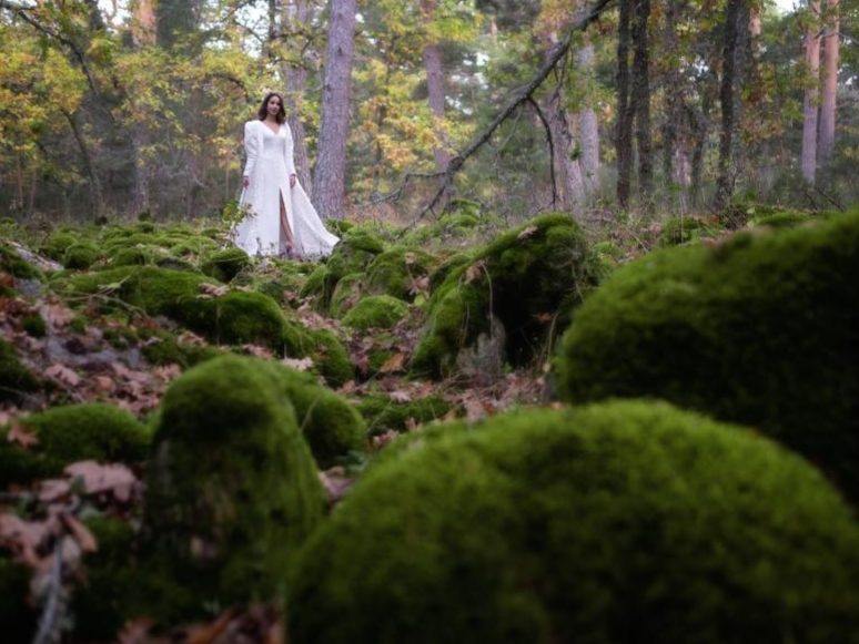 Mujer con vestido blanco posando en medio de la naturaleza